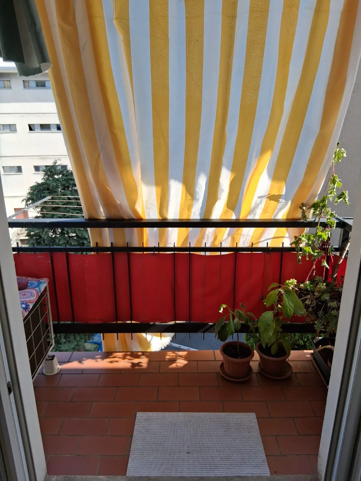 Der kleine private Balkon mit Pflanzen und einem gestreiften Sonnensegel