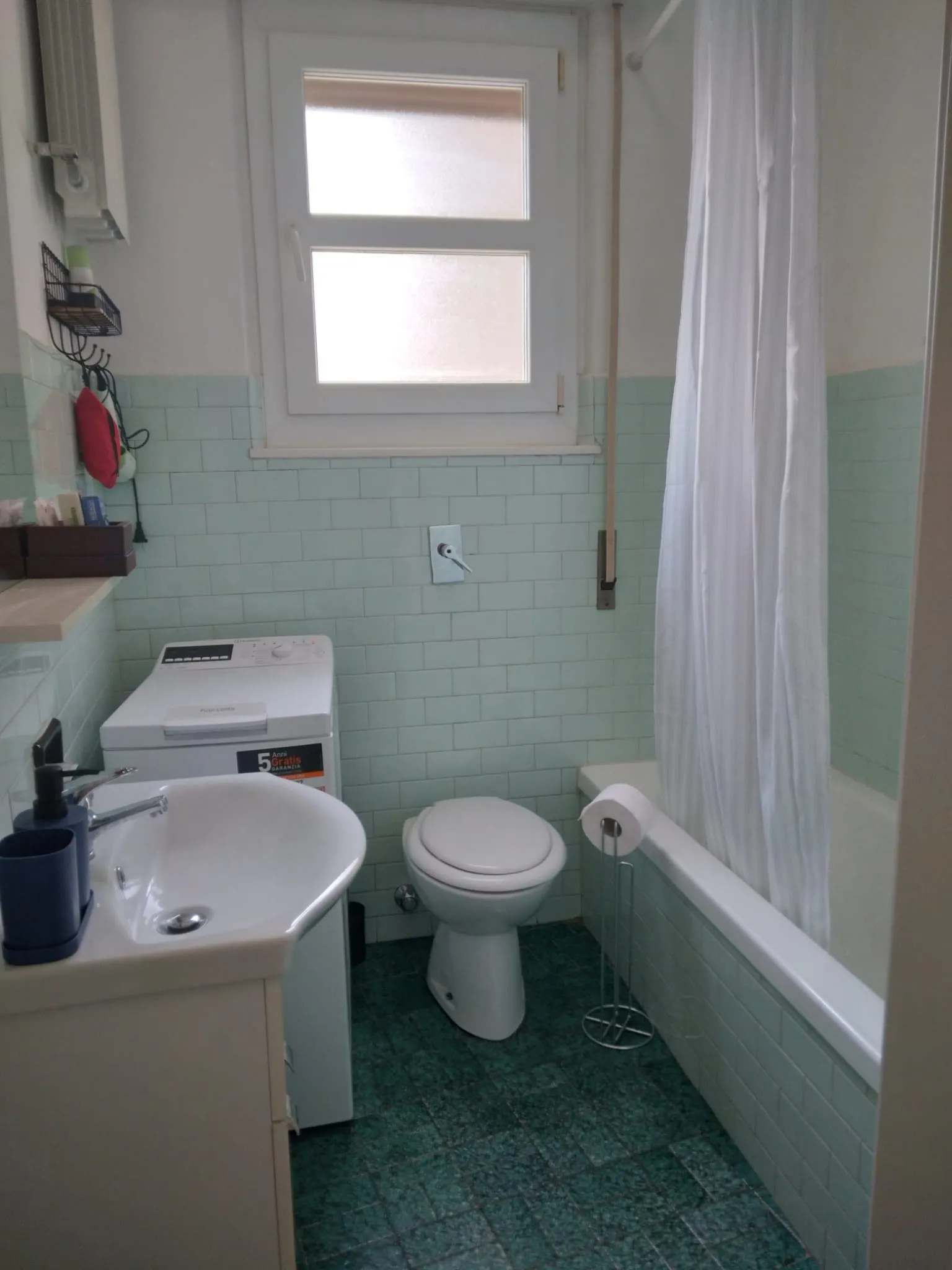 Das Bad mit Badewanne, Fenster und Waschmaschine