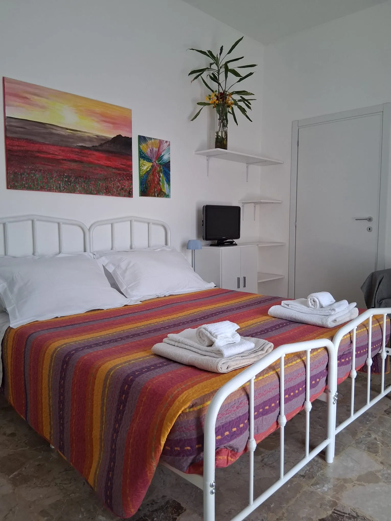 Das Doppelbett mit frischen Handtüchern unter einem farbenfrohen Gemälde