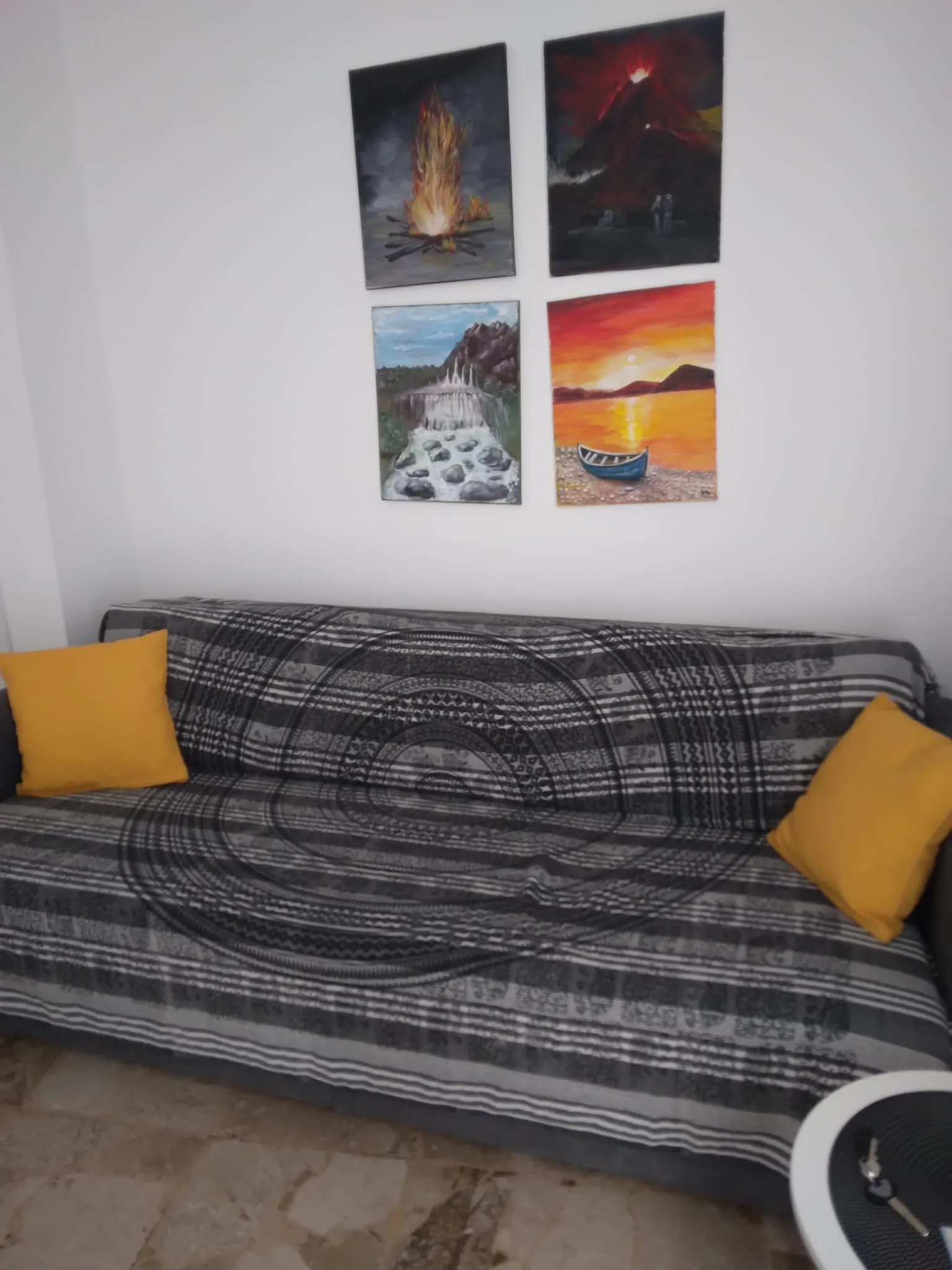 Das Sofa mit gelben Kissen und vier kleinen Bildern